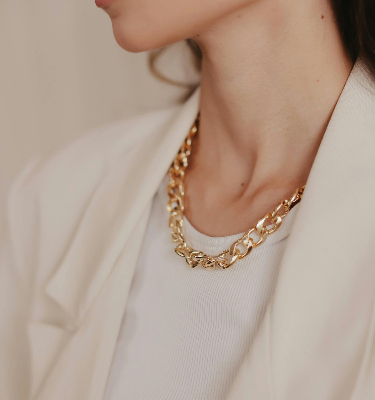 Successful, professional woman styled in an all white outfit with refined gold jewelry.