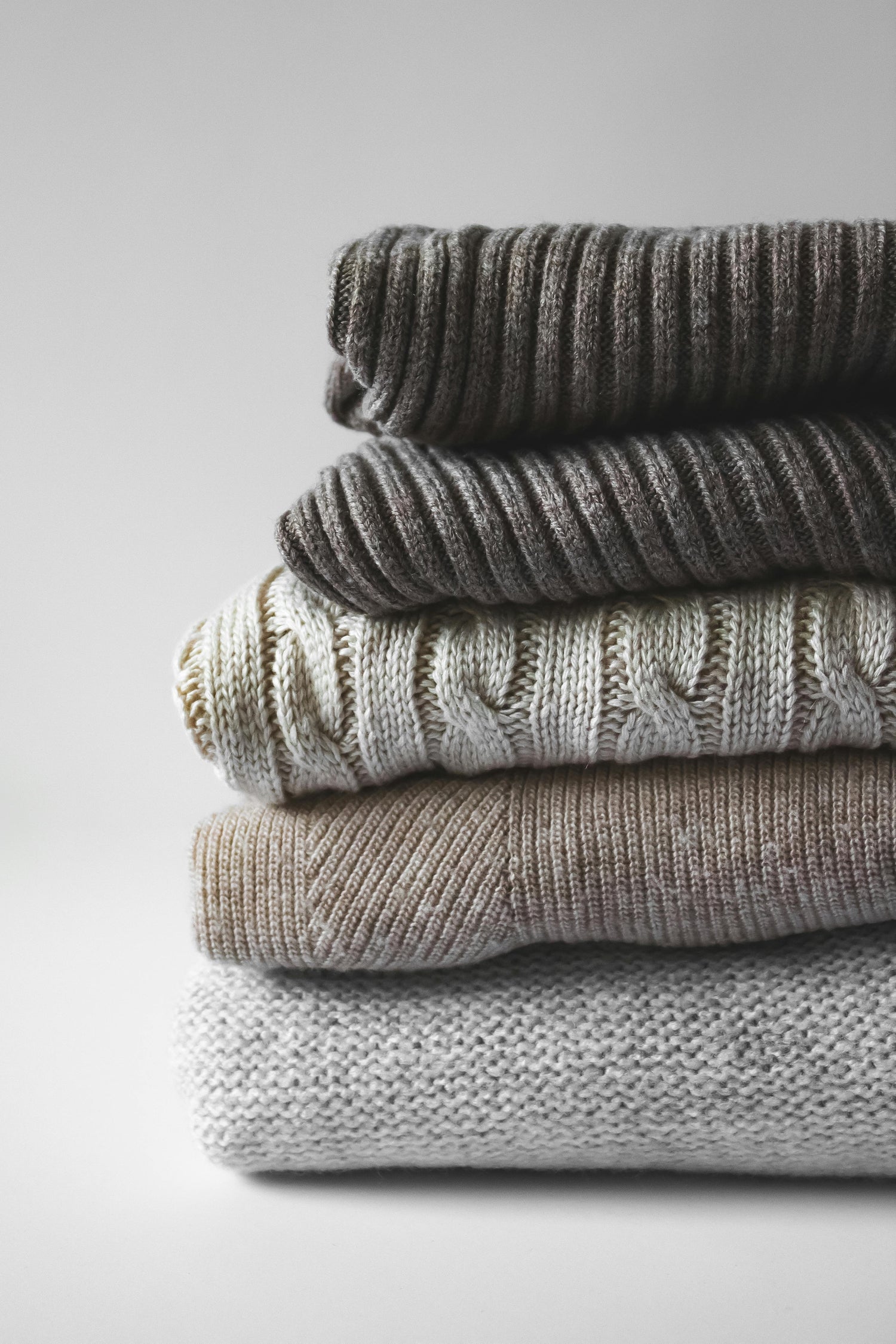 Pile of gray sweaters from sustainable brands curated by Styled After.