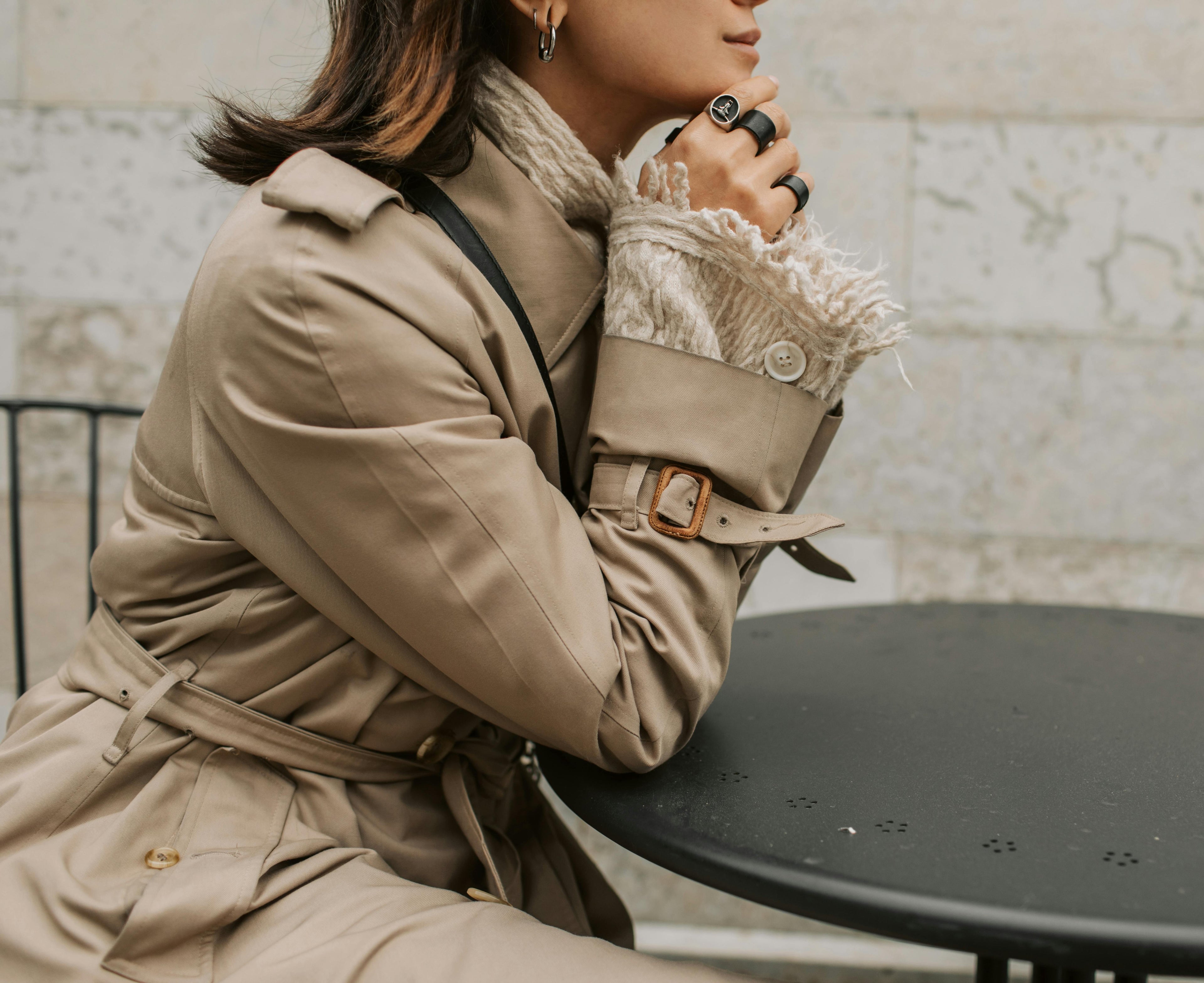 Woman styled with fashionable trench coat and matte black jewelry.